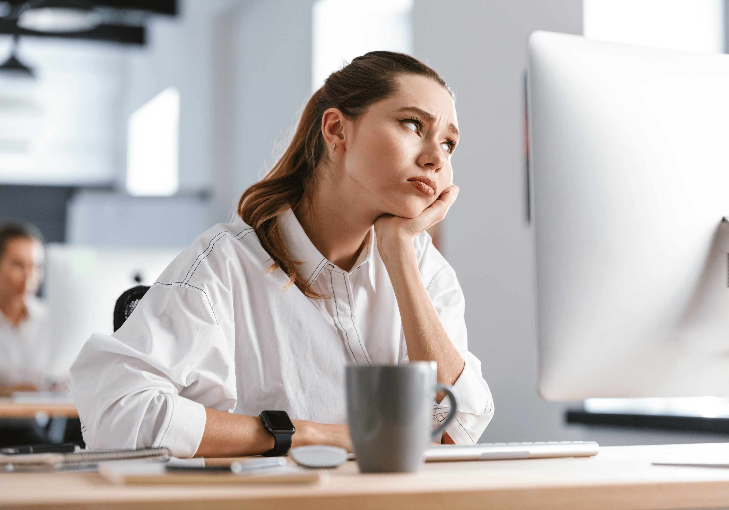 A successful professional woman feeling weary at her desk, representing high achievers who are realizing that success has started costing more than it gives back.