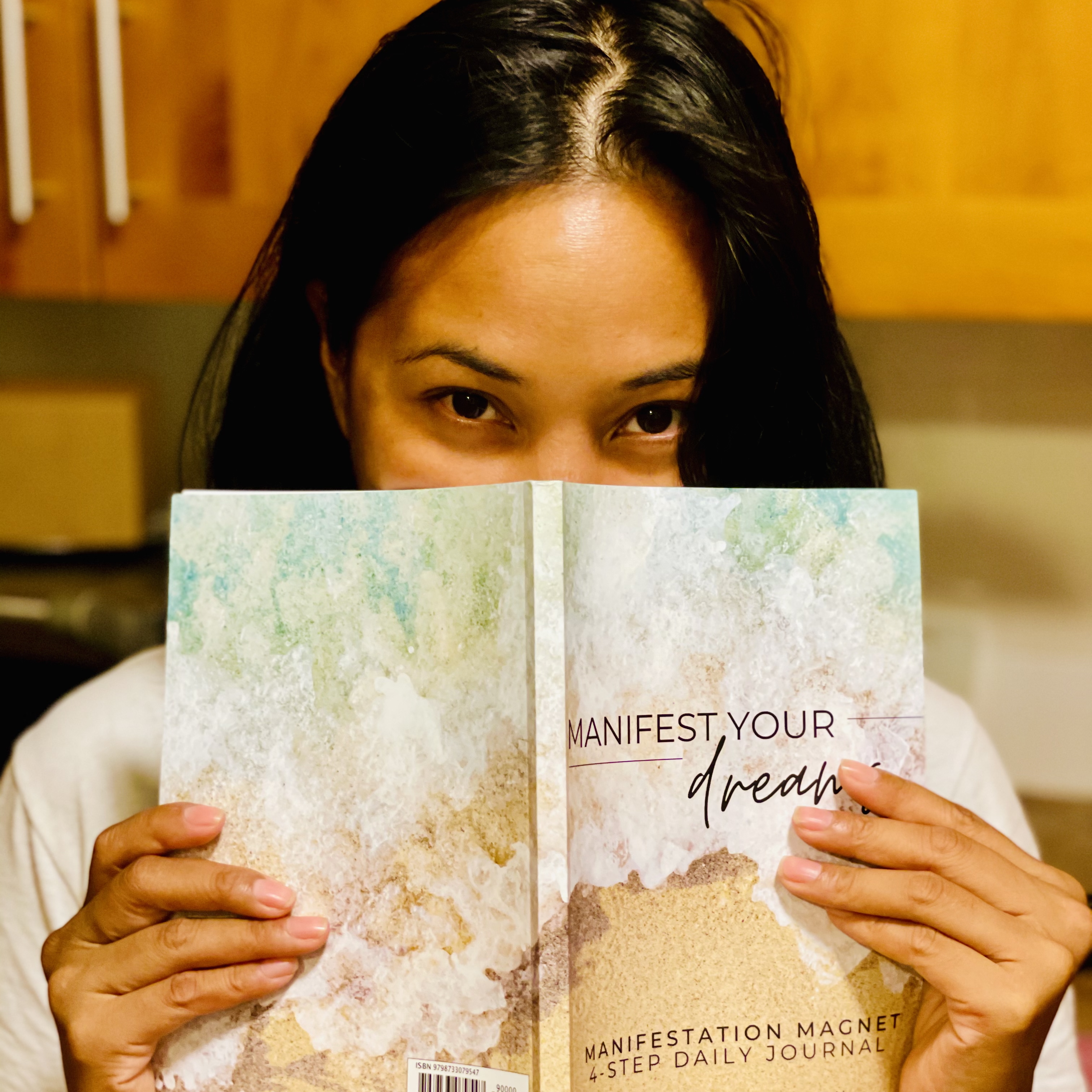 Diana Bejasa, author of the Manifest Your Dreams journal, holding a copy of her book.